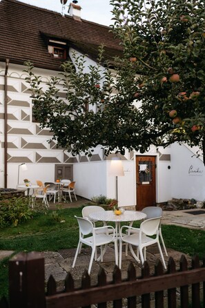 Un patio con un edificio blanco, una puerta de madera y una mesa con sillas.