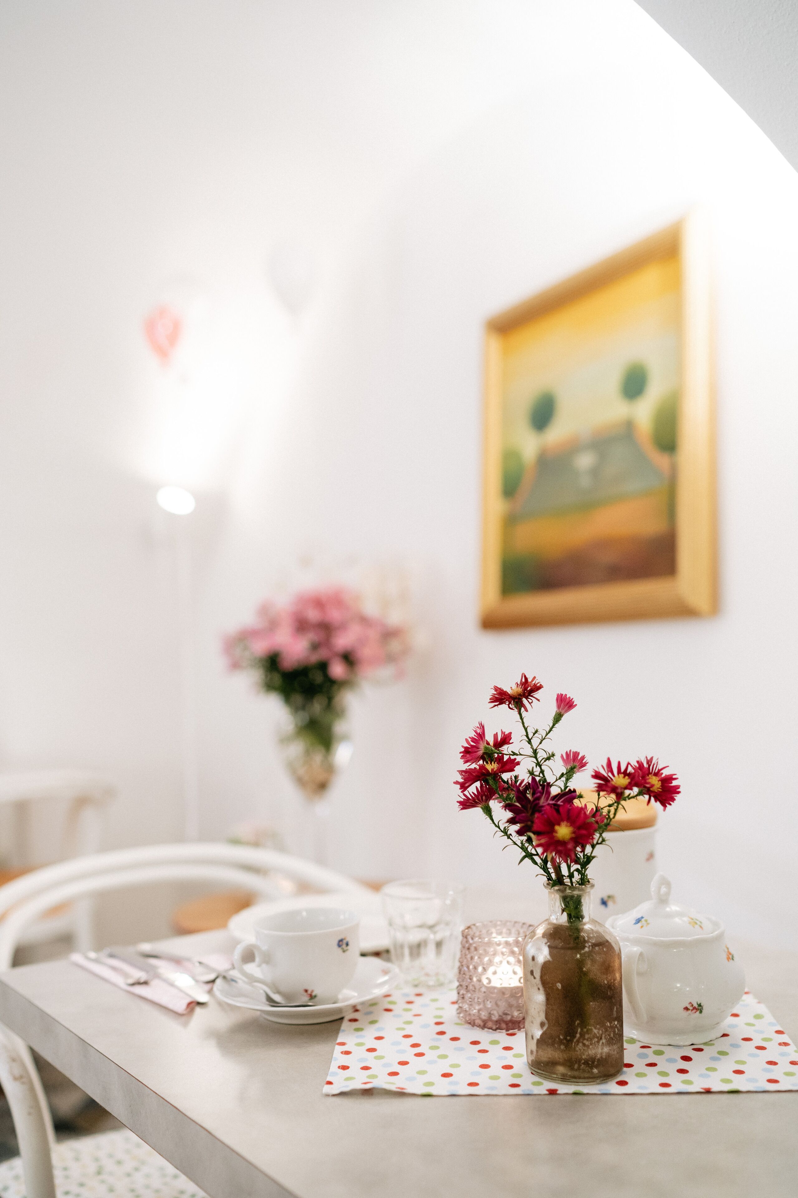 A dining table with a vase of flowers, a teapot, and a cup.