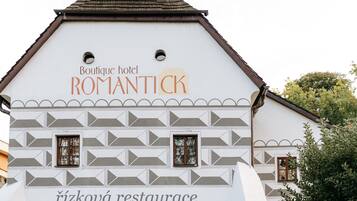 A white building with a roof, labeled "Boutique hotel ROMANTICK" and "rízková restaurant."