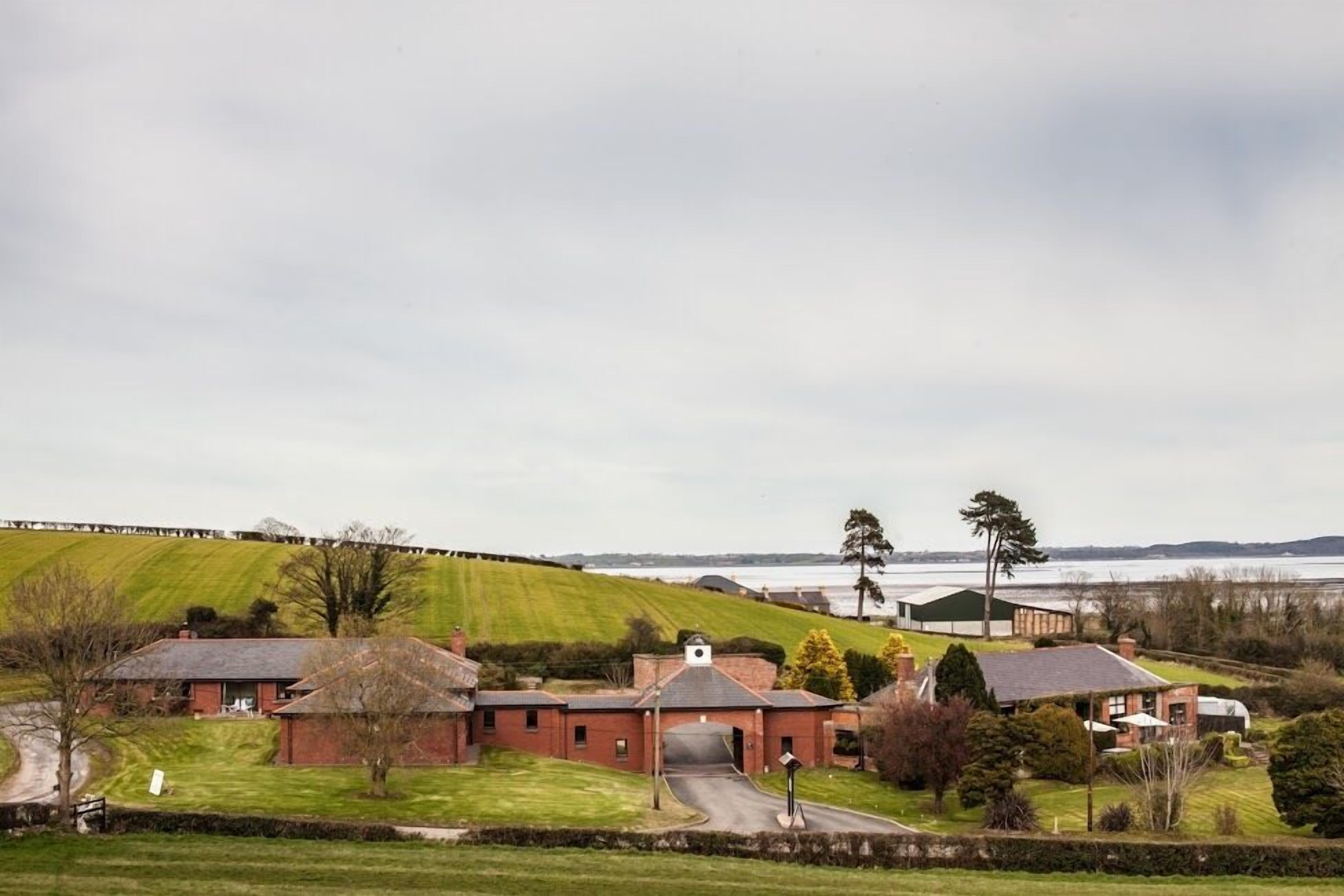 A rural setting with a large brick building, a small house, and a field.