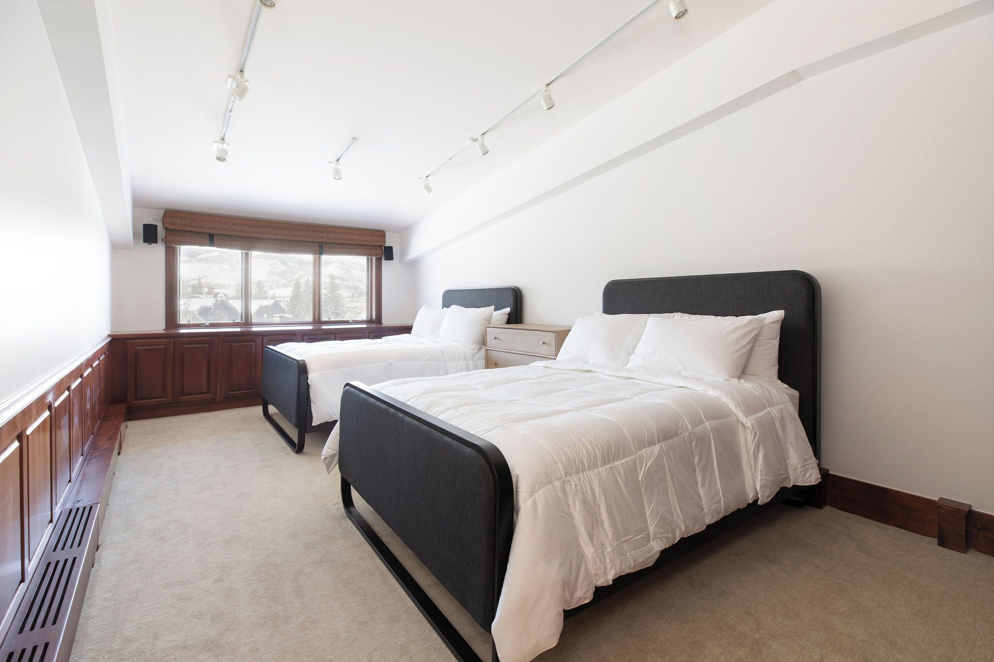 A bedroom with two beds, a window with a view, and a ceiling light fixture.