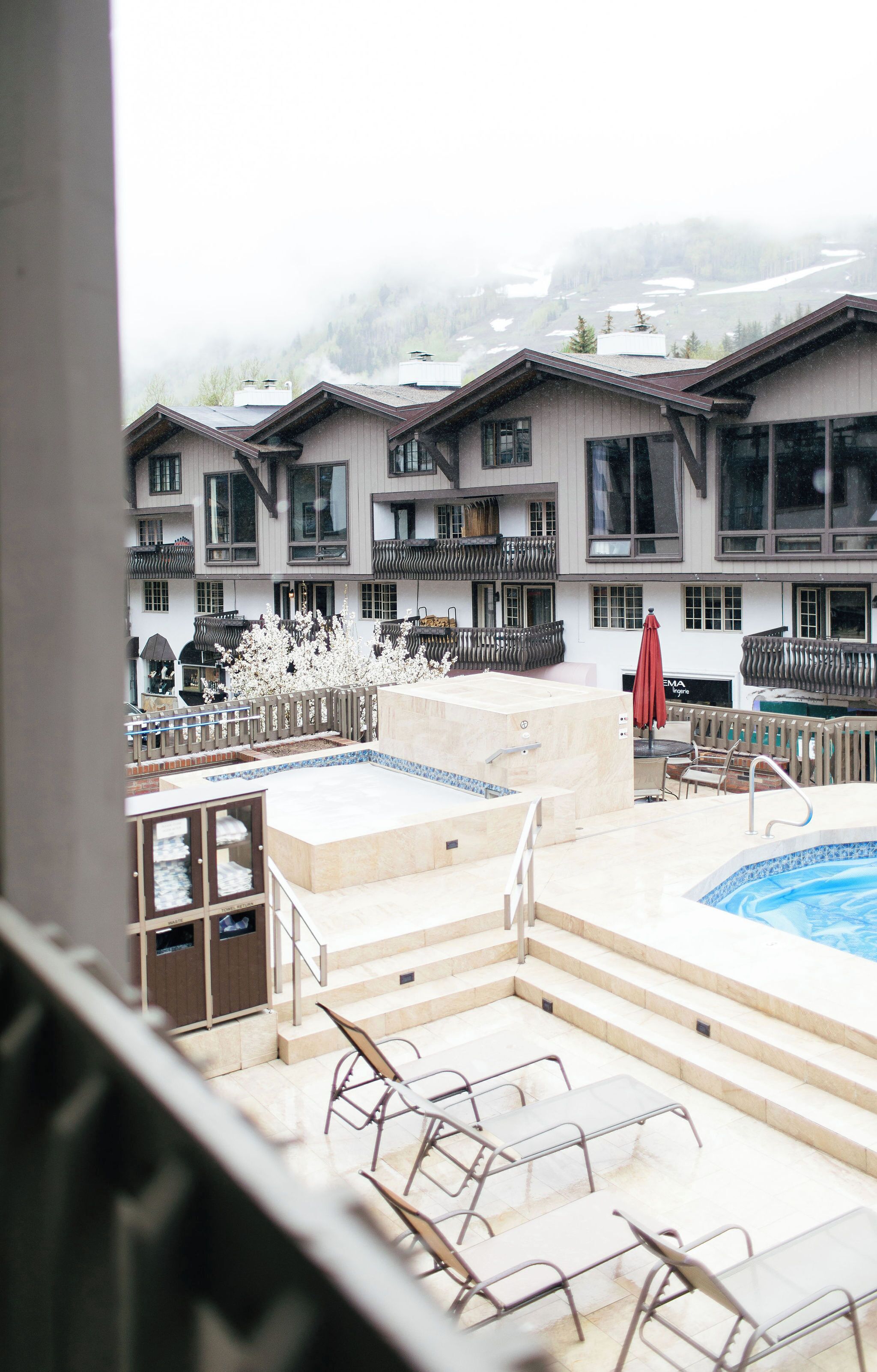 A hotel with a pool area, outdoor seating, and a view of a mountain.