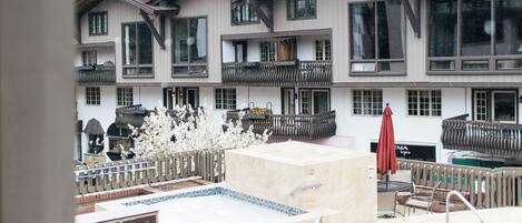 A hotel with a pool area, outdoor seating, and a view of a mountain.