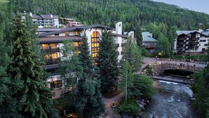 A hotel with multiple buildings, a stone bridge, and a river. - Sitzmark Vail (Vail)