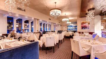 A restaurant with multiple tables, chandeliers, and a patterned floor.