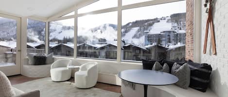 Un interior moderno con ventanas amplias que ofrecen vista a un paisaje montañoso nevado.