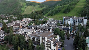 Un pueblo con una mezcla de edificios modernos y tradicionales, rodeado de colinas verdes exuberantes y un cielo despejado.