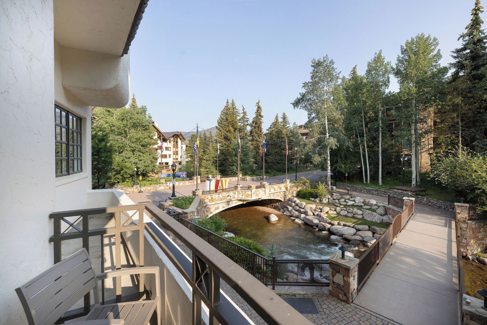 A riverside walkway with a bridge, benches, and a stone wall.