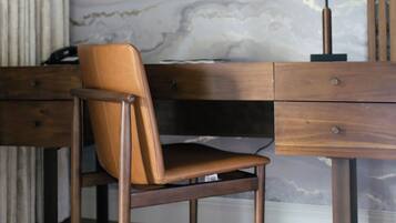 A modern room with a marble wall, a wooden desk, a leather chair, and a lamp.