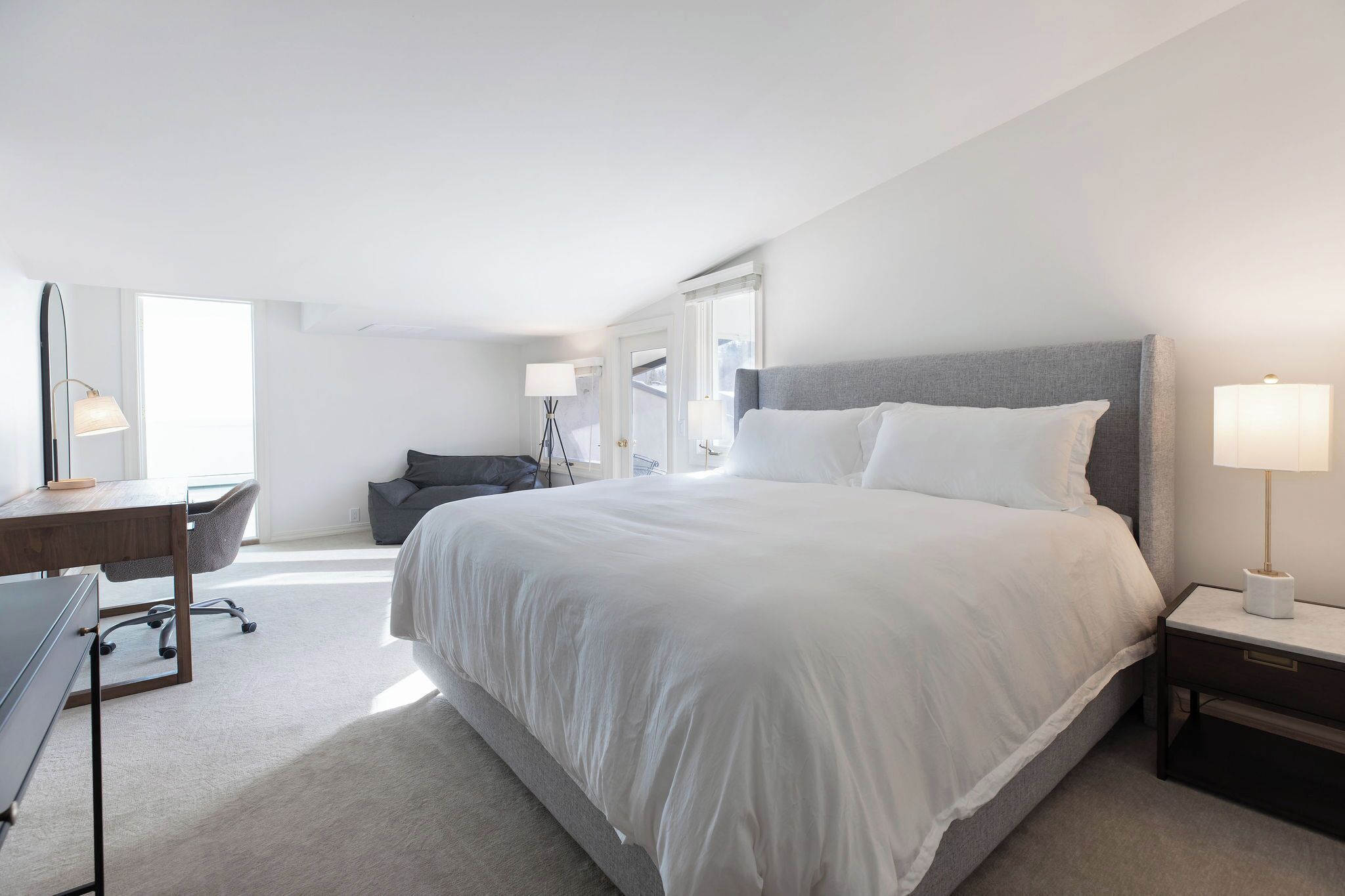 A modern hotel room with a large bed, a desk, and a chair.