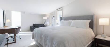 A modern hotel room with a large bed, a desk, and a chair.