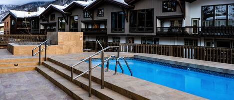 A pool area with steps leading to a building with balconies and large windows.