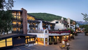 A hotel with a covered outdoor seating area, a ski lift, and a mountain backdrop. - Sitzmark Vail (Vail)