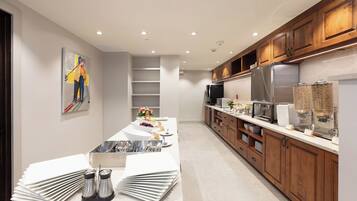 A modern kitchen with a marble countertop, stainless steel appliances, wooden cabinets, and a painting on the wall.