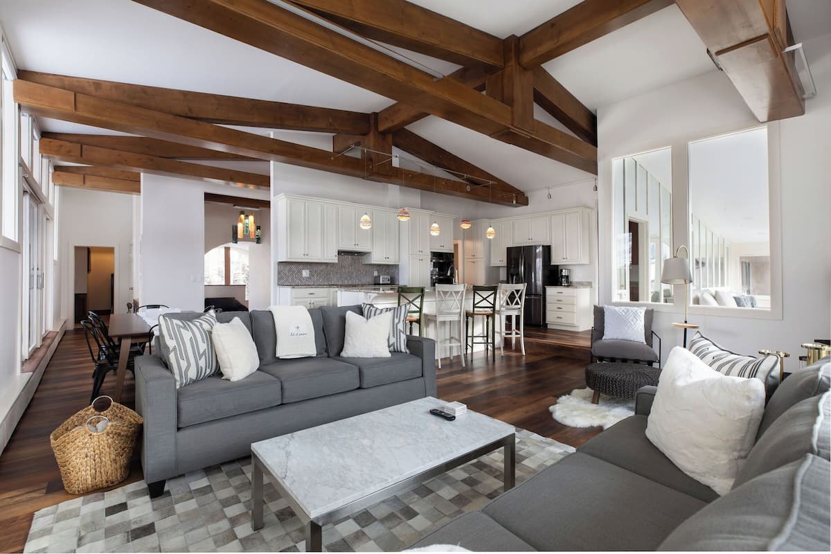 A spacious living area with a grey sofa, a coffee table, and a dining area in the background.