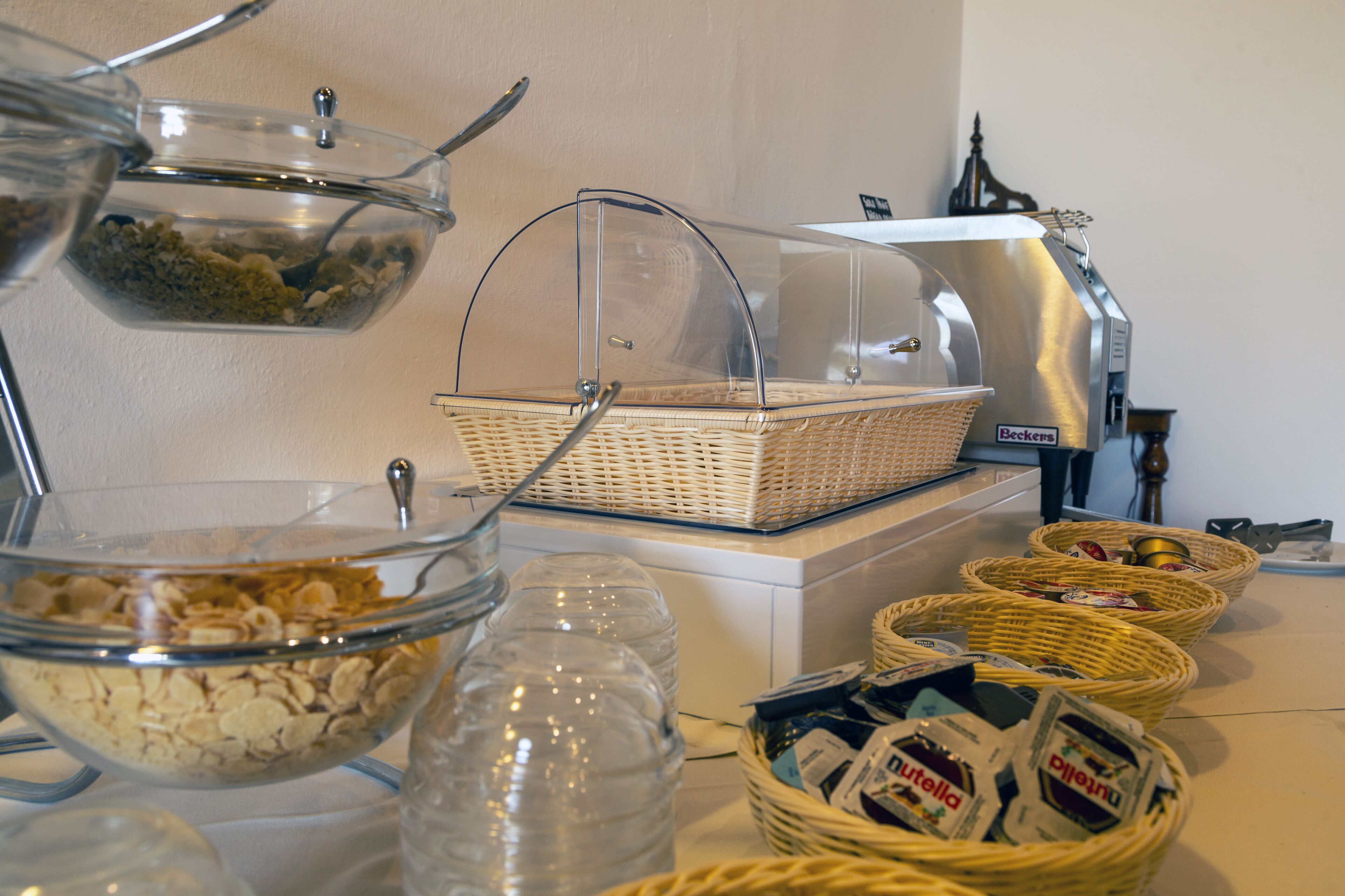 A buffet setup with various food items and containers, including a wicker basket and clear glass bowls.