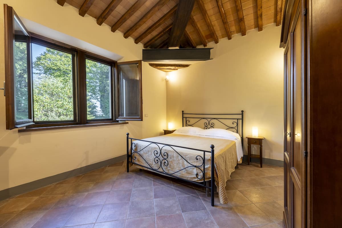 A bedroom with a bed, a window, a nightstand, and a wardrobe.