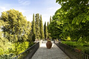 A pathway lined with trees and a large pot in the center. - Villa Montarioso (Monteriggioni)