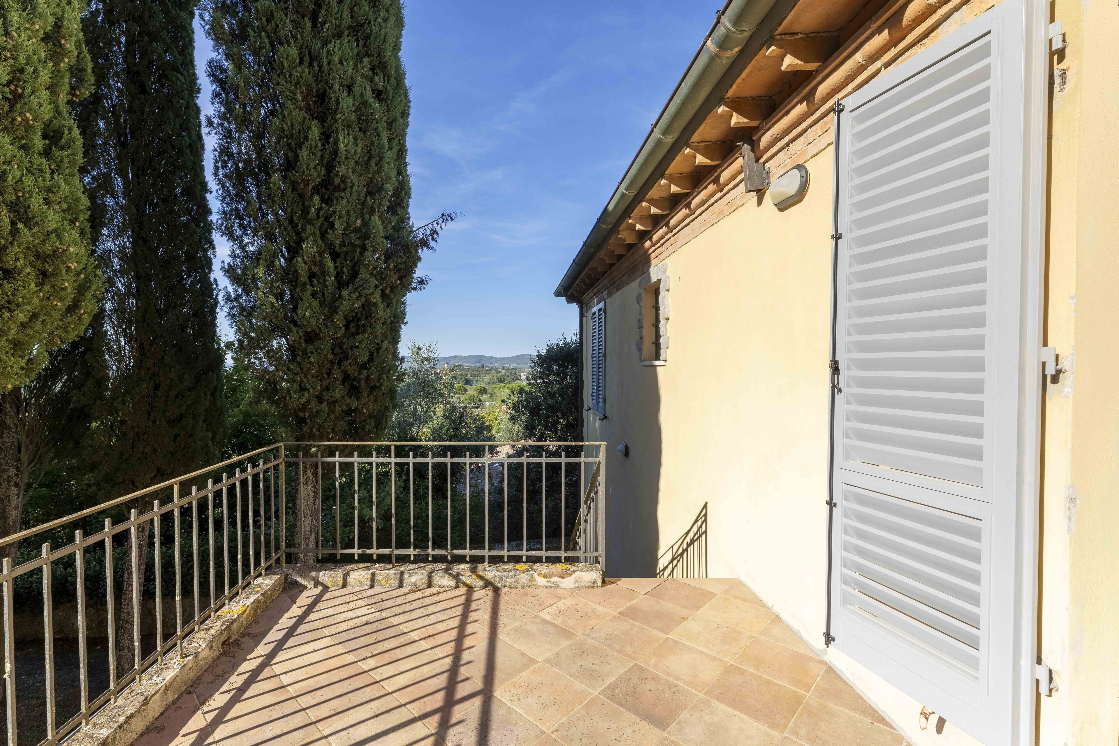 Un balcon avec une balustrade en métal, un sol carrelé et une porte de garage blanche.