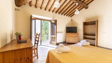 Una camera da letto con un letto, una scrivania con un portatile, una TV e un armadio.