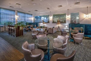 Un espace de détente moderne avec des canapés en cuir, une table basse en verre et un bar doté de tabourets.