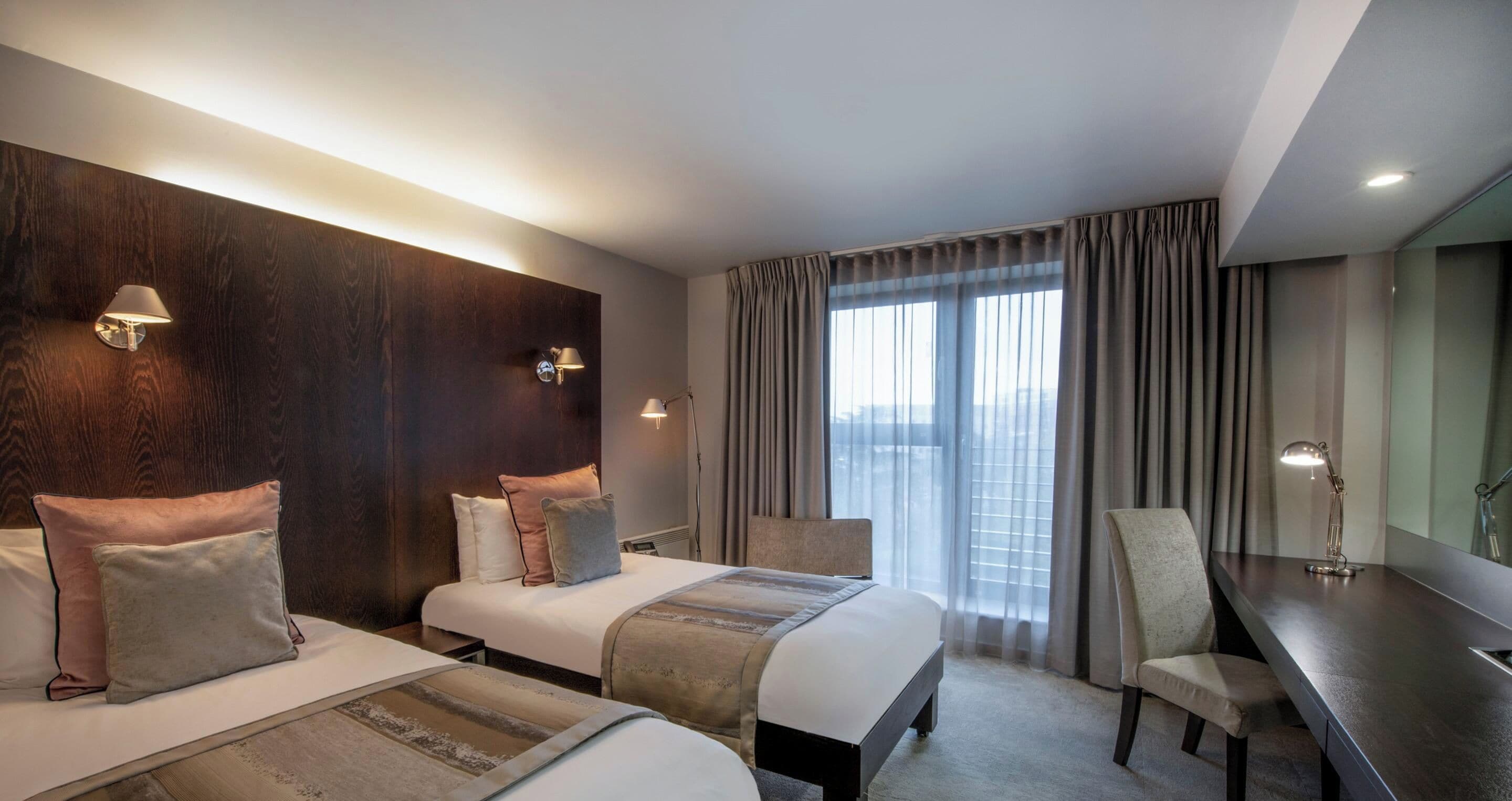 Ein Hotelzimmer mit zwei Betten, einem Schreibtisch und einem Stuhl.