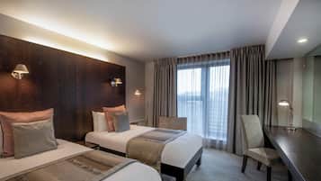 A hotel room with two beds, a desk, and a chair.