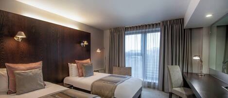 Ein Hotelzimmer mit zwei Betten, einem Schreibtisch und einem Stuhl.