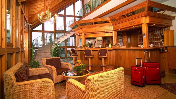 Een houten interieur met rieten meubels, een bar en een trap.