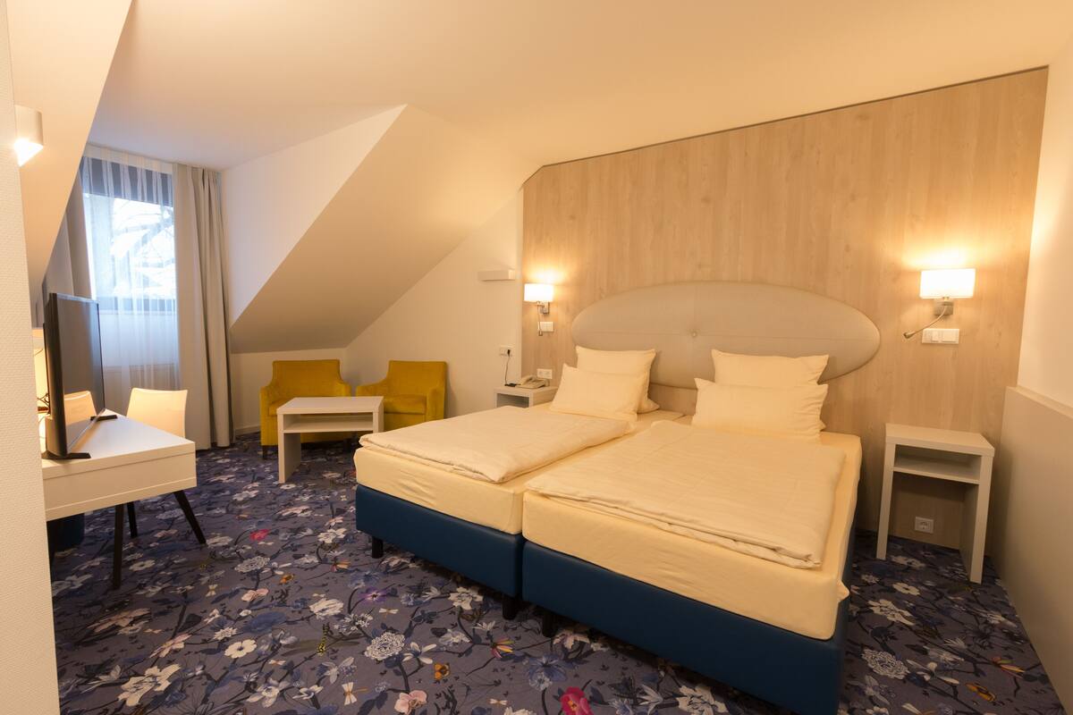 Een hotelkamer met een groot bed, twee nachtkastjes, een bureau en een stoel.