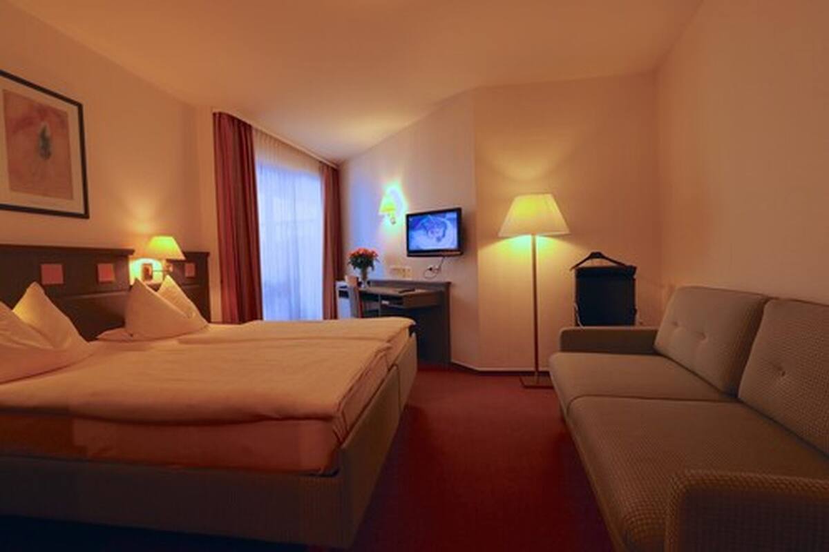 Een hotelkamer met een bed, een bureau, een televisie en een bank.