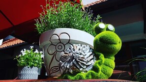 Una planta en maceta con un diseño decorativo, un peluche que se asemeja a un personaje famoso y una pequeña planta en maceta con flores blancas.