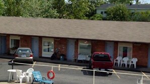 A swimming pool with lounge chairs and a lifebuoy, surrounded by a fence. - Caravan Inn Motel (Niagara Falls)