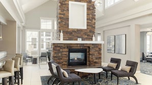 Un amplio espacio interior con chimenea de piedra, asientos cómodos y ventanas grandes.