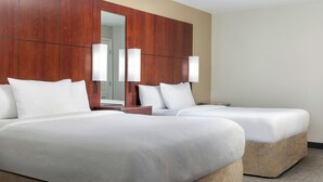 Habitación de hotel con dos camas, un espejo grande y un armario de madera.