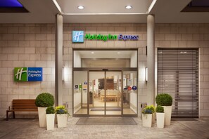 The entrance to a Holiday Inn Express hotel with a modern design, featuring a glass door entrance, a bench, and potted plants. - Holiday Inn Express Nuernberg-Schwabach by IHG (Schwabach)