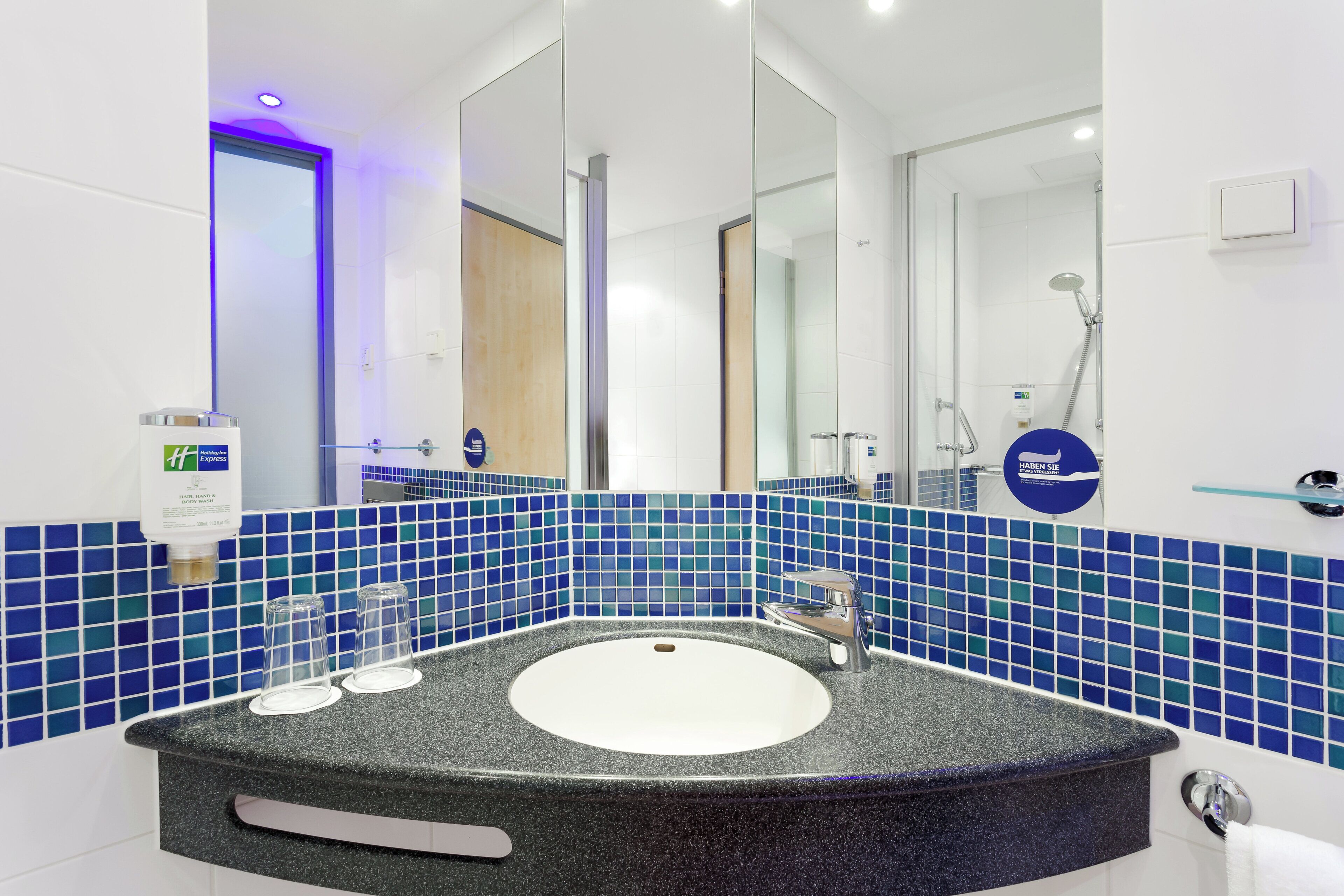 Une salle de bain moderne avec un lavabo rond, un grand miroir et un espace douche.