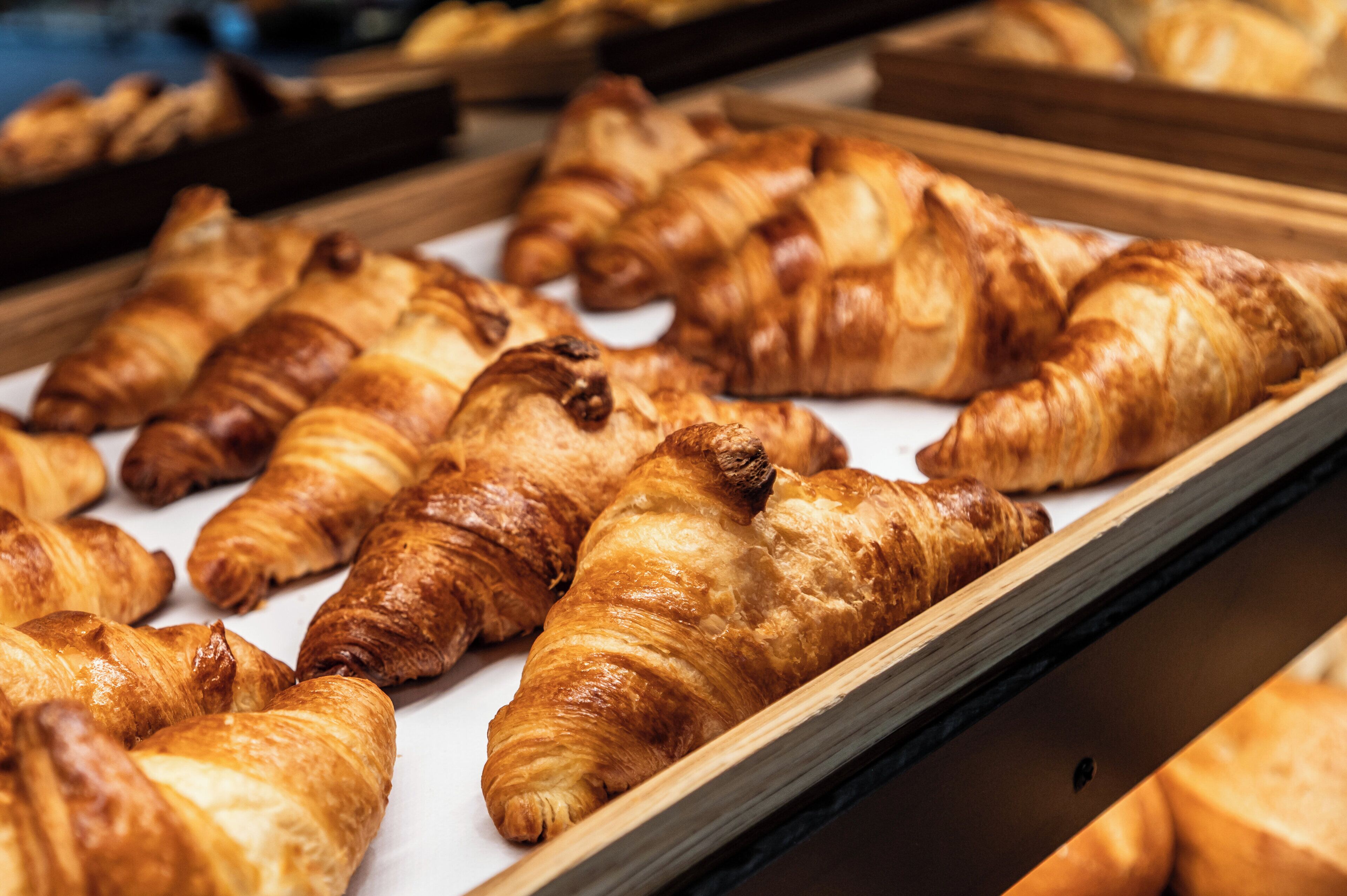Une variété de pâtisseries, notamment des croissants et d’autres viennoiseries, présentées sur des plateaux.