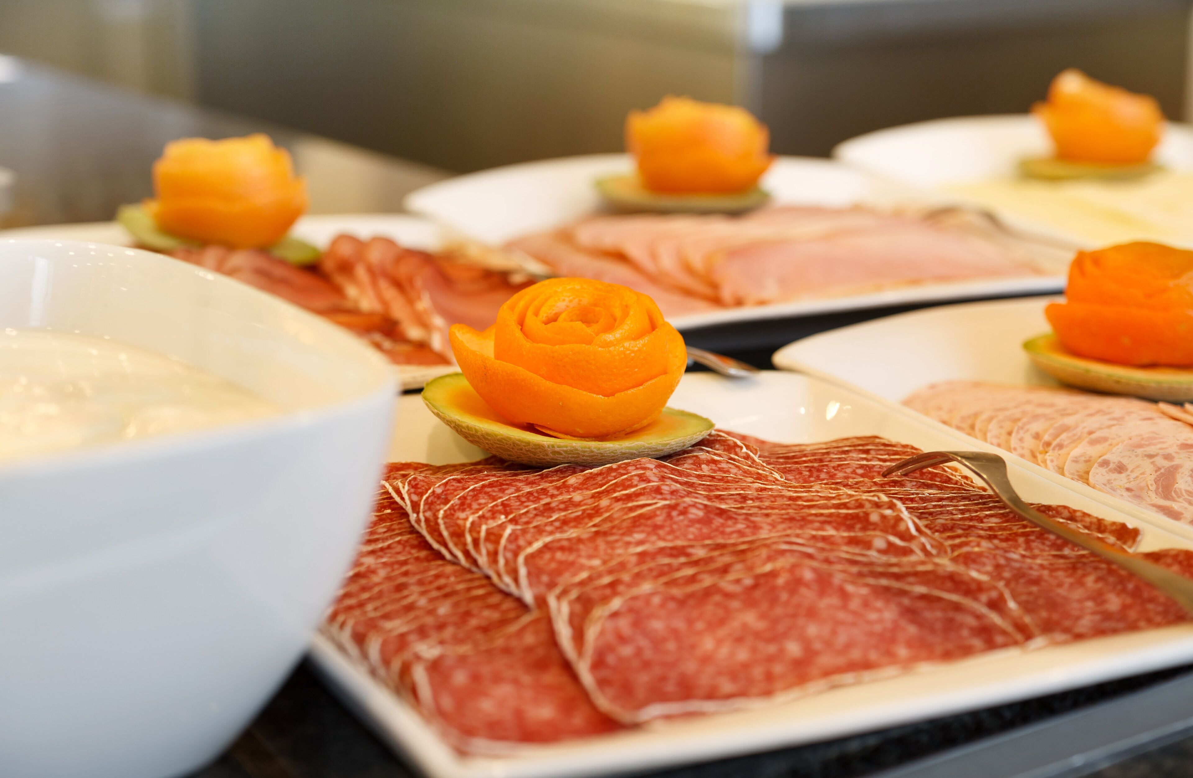 A buffet with various meats and a bowl of dip.