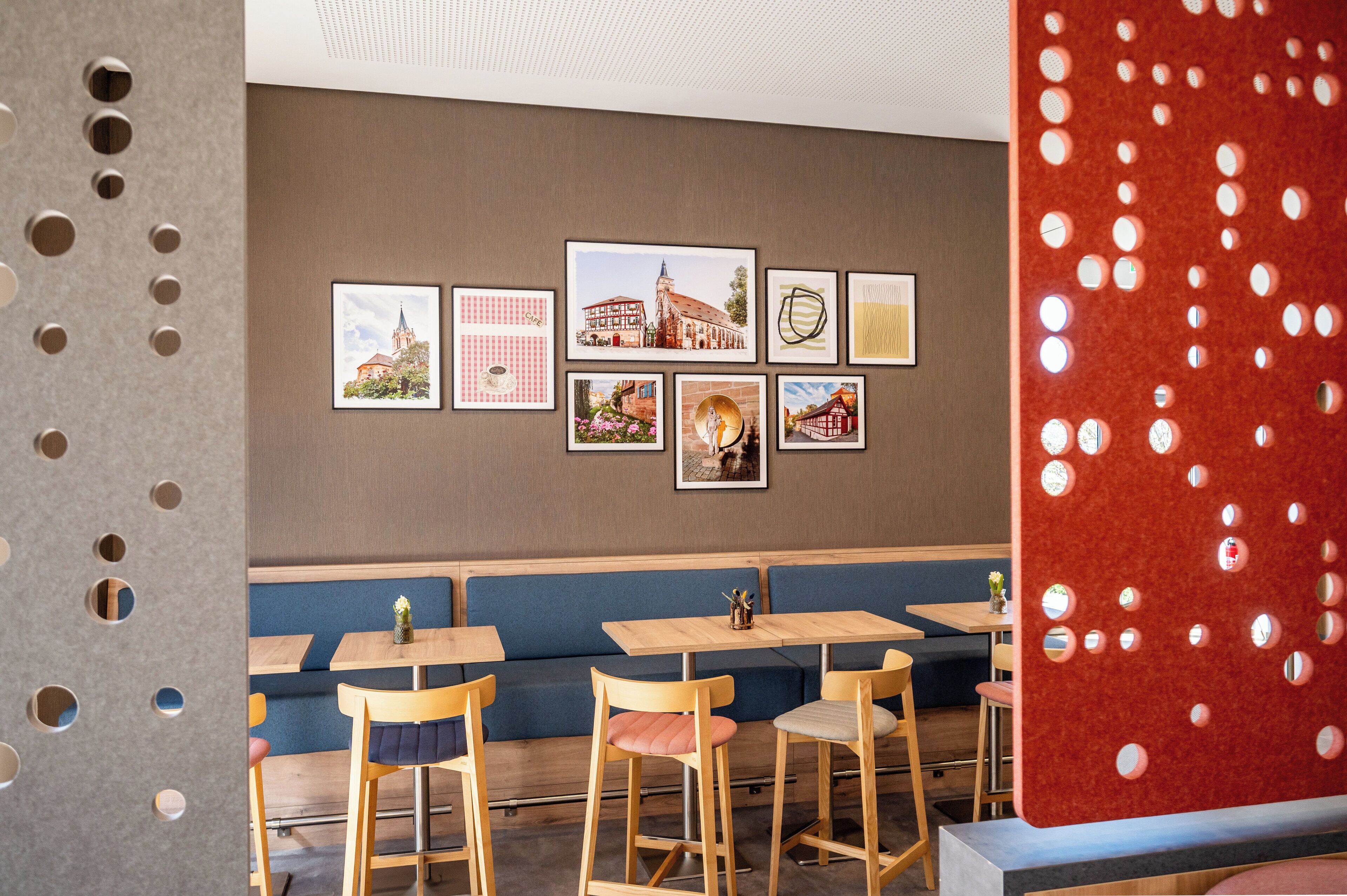 Interior de un restaurante con cabinas, mesas y cuadros en la pared.