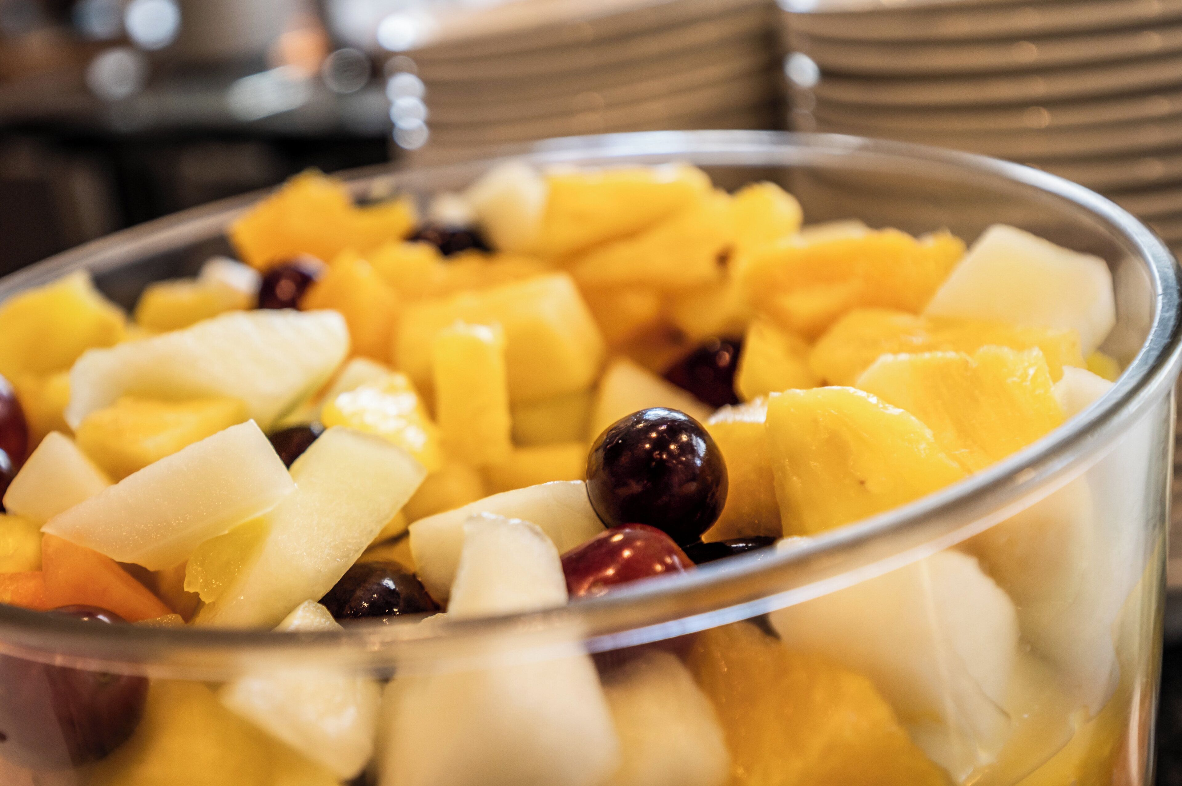 A clear glass bowl filled with diced fruits and nuts.