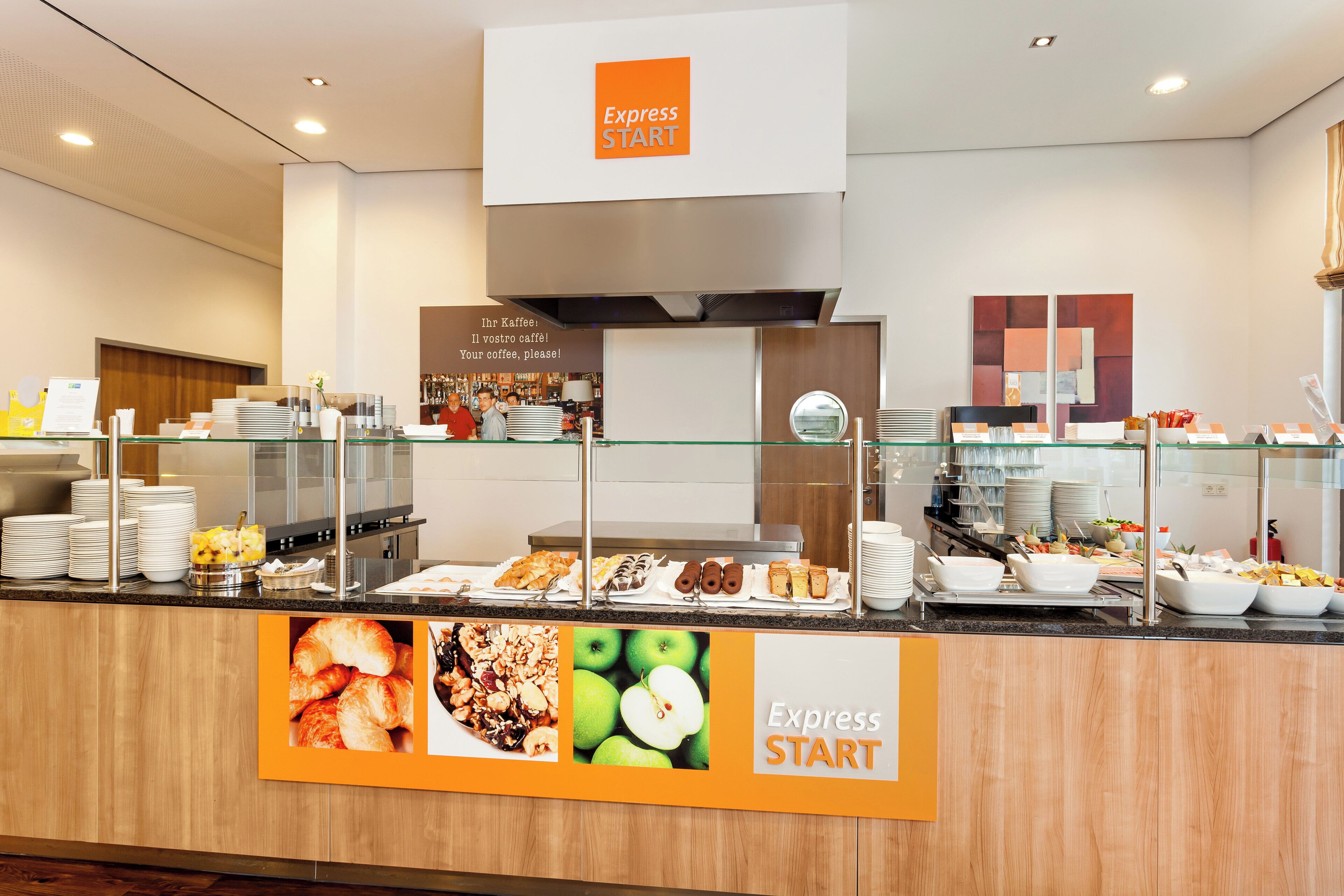 A buffet area with a variety of food options, including pastries and fruits, and a sign that reads 'Express START'.
