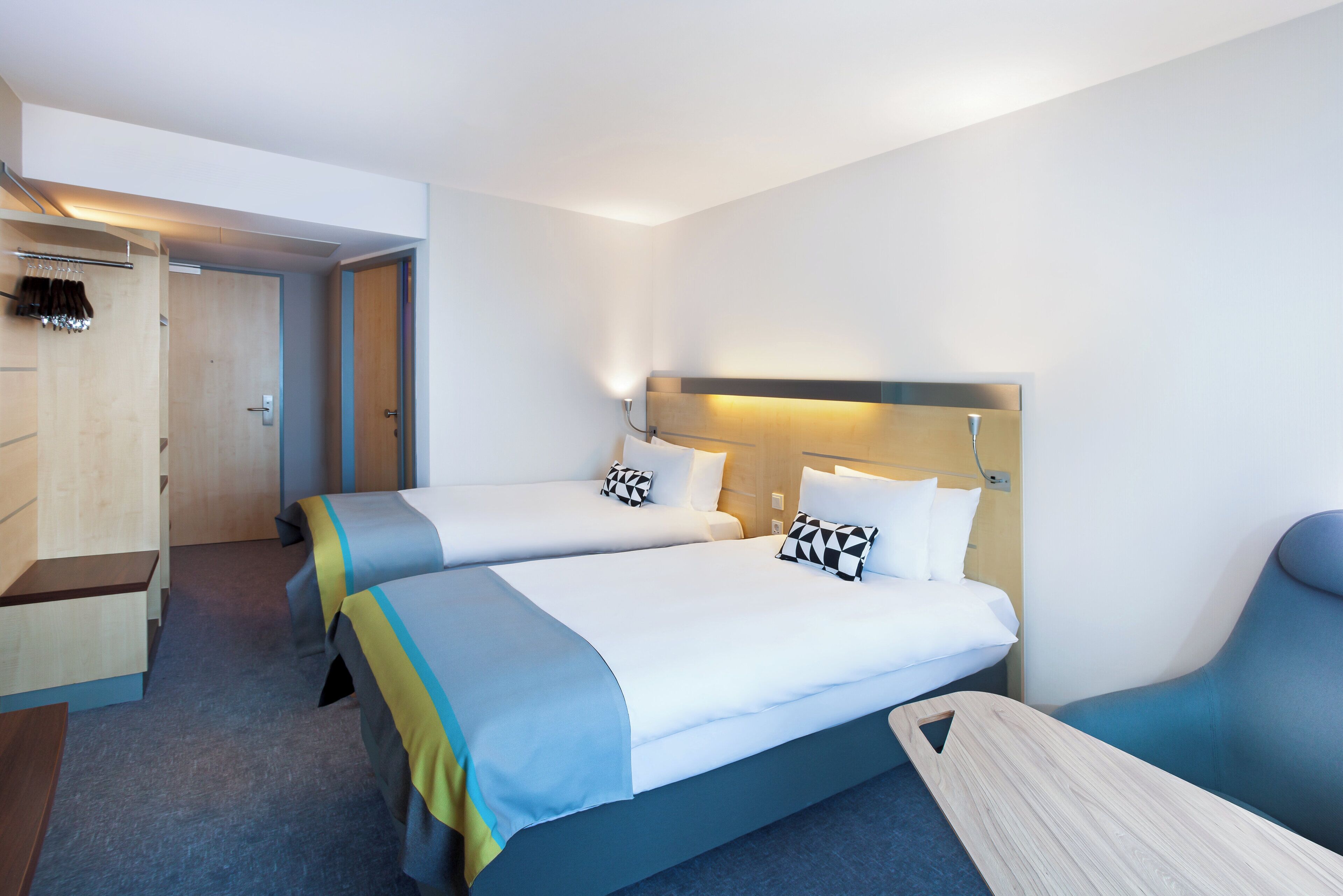 A hotel room with two beds, a desk, and a chair.