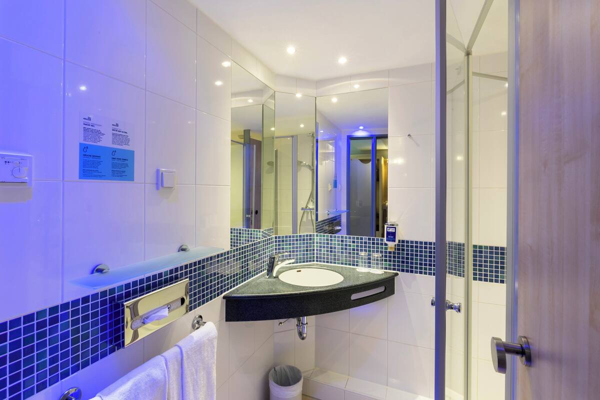 A modern bathroom with a curved sink, glass shower enclosure, and a mirror reflecting the room.