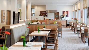 Un restaurante con varias mesas y cabinas, una zona de bar y una estación de café.