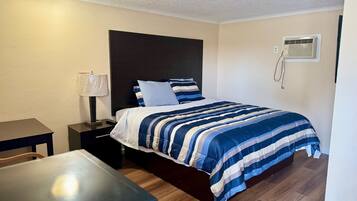 Quarto de hotel bem arrumado, com cama, mesa de cabeceira, abajur e uma pequena mesa.