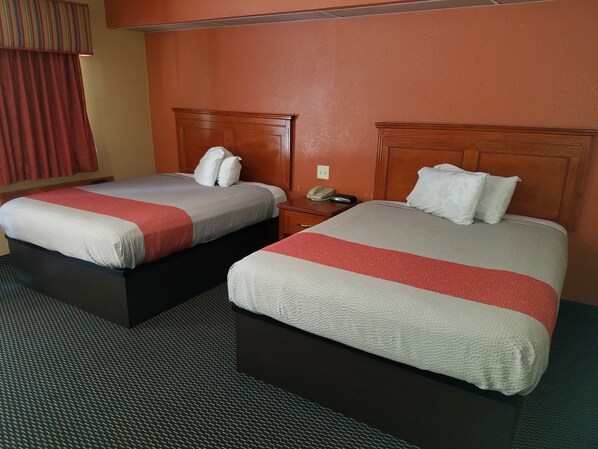 Two single beds with wooden headboards, a bedside table with a lamp, and a telephone.
