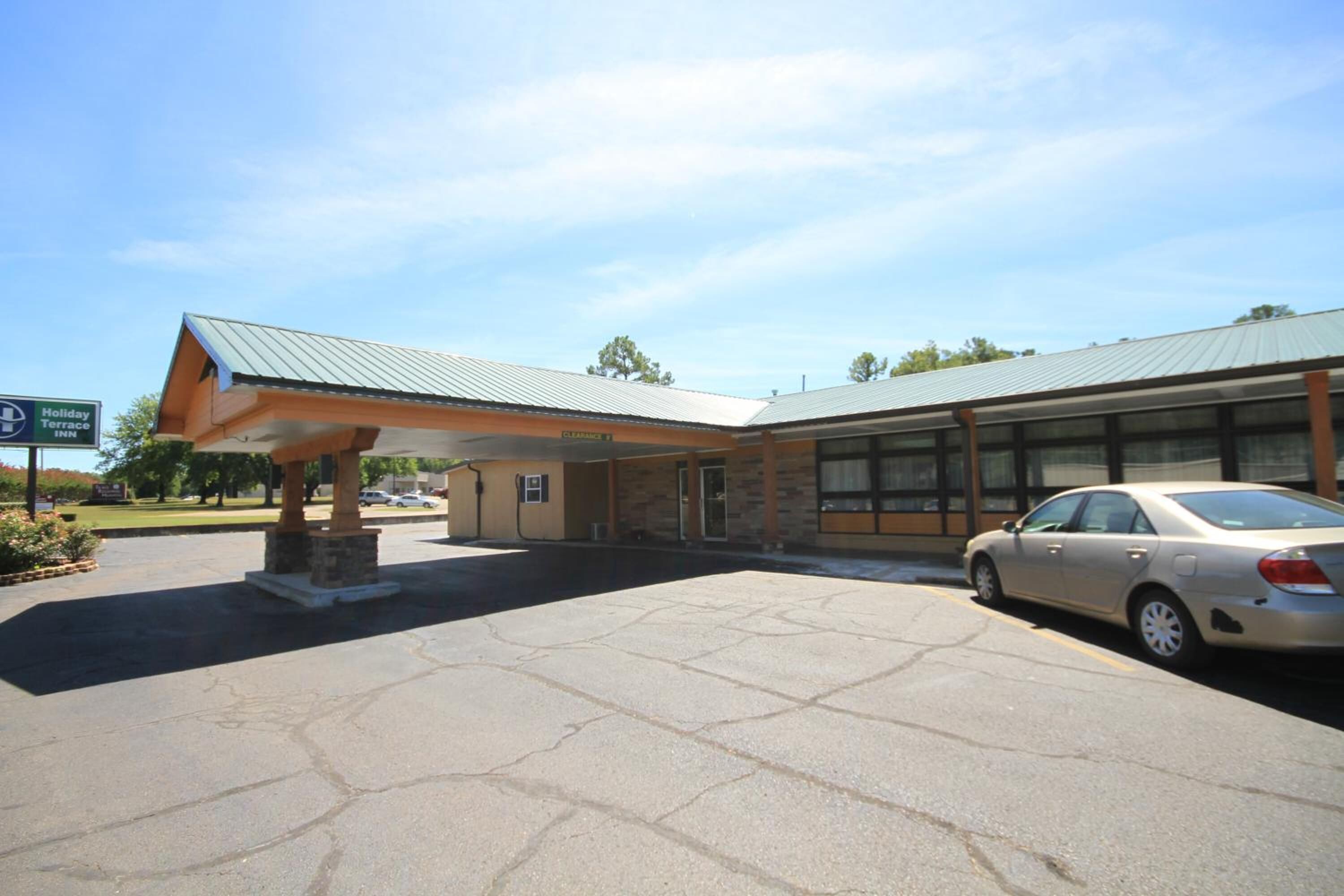 A Holiday Inn with a covered entrance, a parking lot, and a car parked in front.