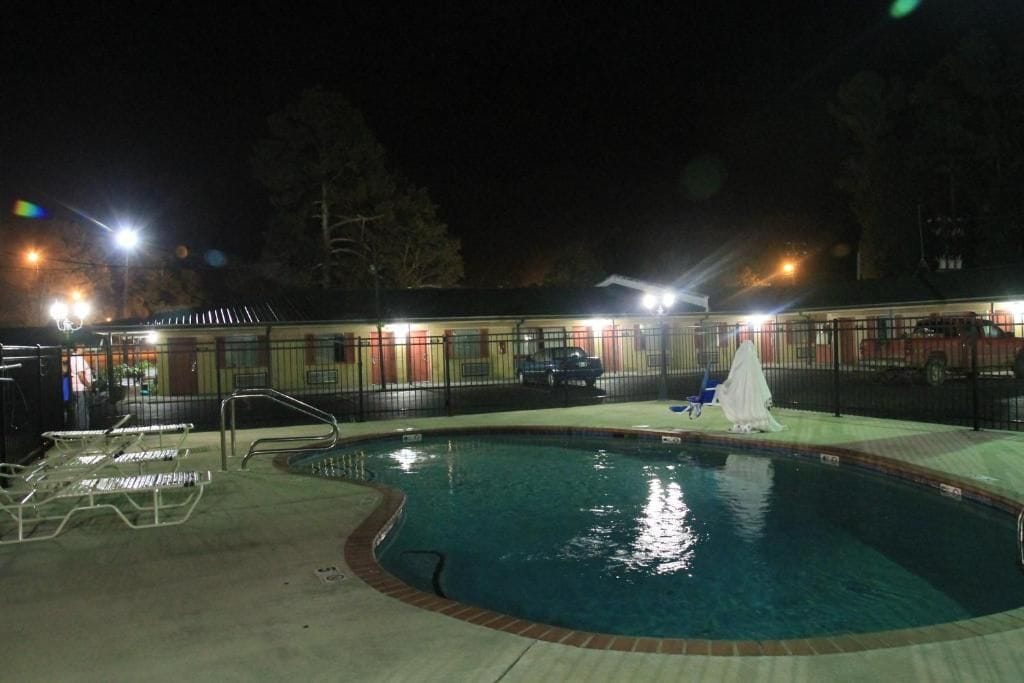 A swimming pool with a fenced area, lounge chairs, and a covered seating area.