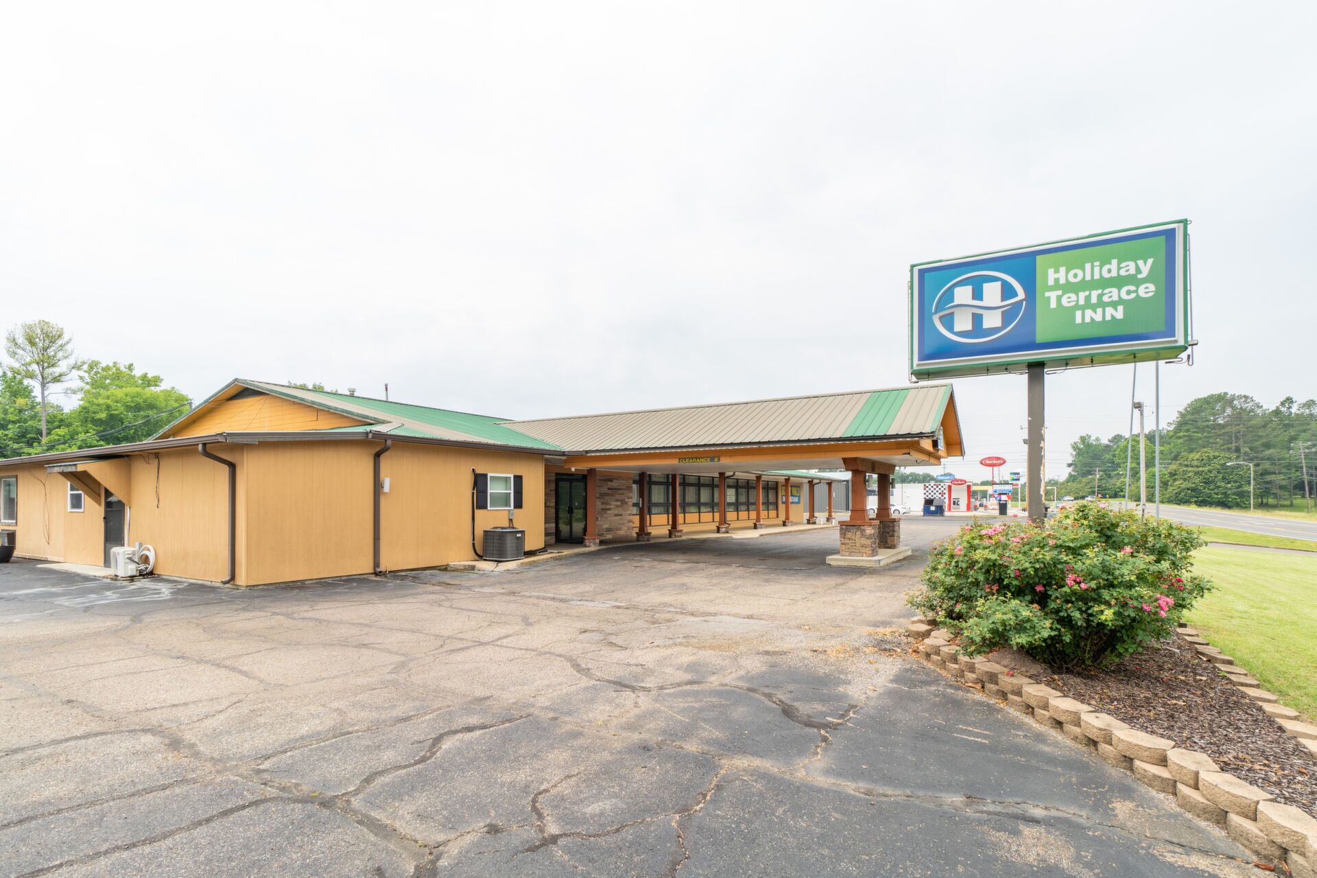 A Holiday Inn Terrace Inn with a covered parking area and a small garden.